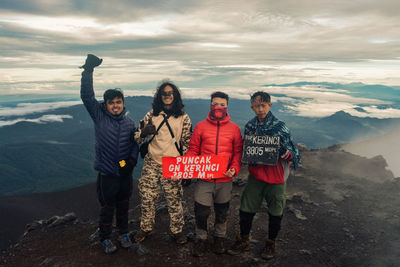 Portrait of friends standing on mountain against sky. mount kerinci 3805 masl