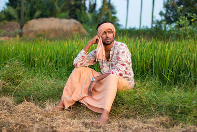 Portrait of smiling young woman sitting on field