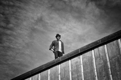 Low angle view of man standing on building against sky