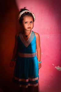 Portrait of teenage girl standing against red wall