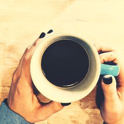 Midsection of man holding coffee cup on table