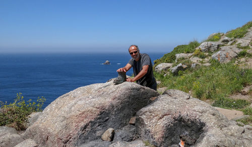 Portrait of man standing at beach against clear blue sky