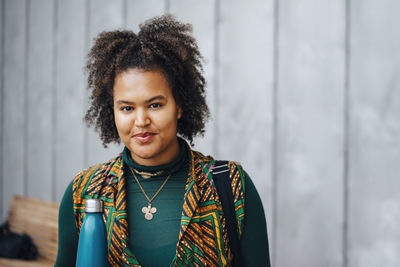 Portrait of young woman standing against wall