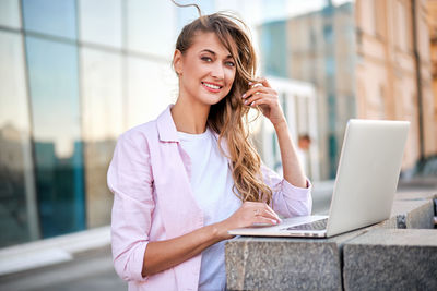 Portrait of smiling young woman using mobile phone