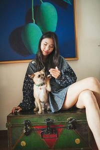 Portrait of young woman sitting on wall