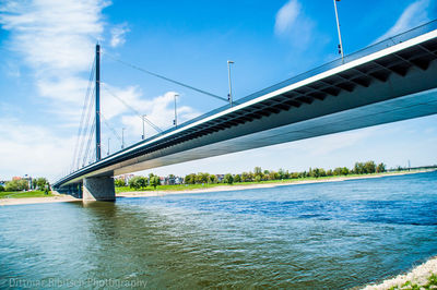 Low angle view of suspension bridge over river against sky