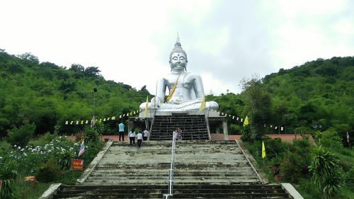 Statue amidst trees and buildings against sky