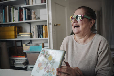 Happy senior woman wearing broken sunglasses at home