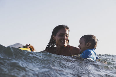 Intimate portrait of mother and son playing at sea