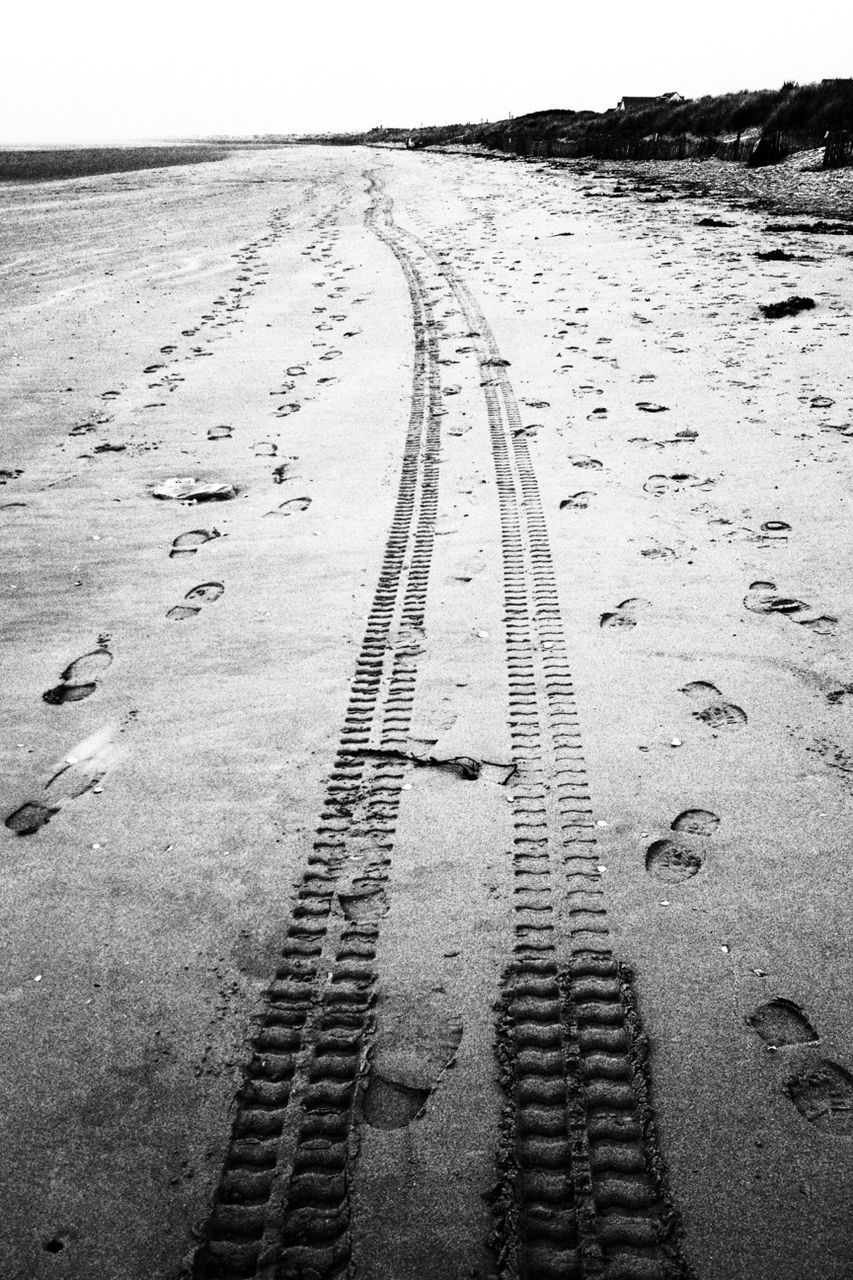 the way forward, diminishing perspective, vanishing point, road, tranquility, sand, transportation, shadow, footprint, tranquil scene, high angle view, landscape, sunlight, day, nature, street, outdoors, road marking, asphalt, clear sky