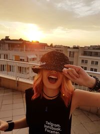 Woman screaming while standing on terrace in city against sky