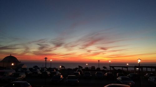 Silhouette cars parked at beach against sky during sunset