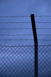 Low angle view of chainlink fence against clear blue sky