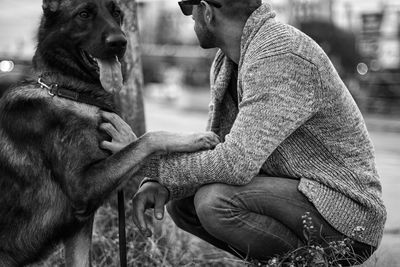 Side view of young man with dog crouching on street