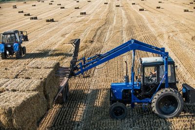 High angle view of tractor with hay bales on field