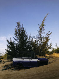 Boat moored on field against clear blue sky