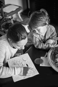 High angle view of boy looking at mother writing on paper