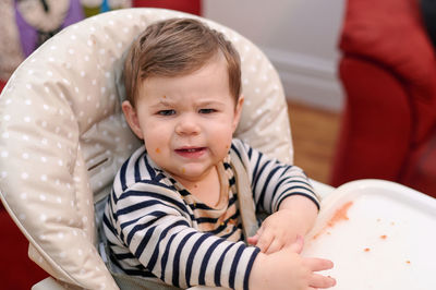 Cute young toddler eating in his high chair