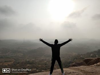 Rear view of man standing on mountain against sky