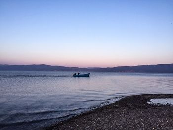 Motorboat sailing in sea against clear sky during sunset