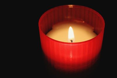 Close-up of lit candle against black background