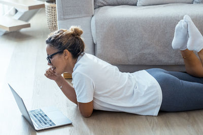 Young woman using laptop while sitting on bed at home