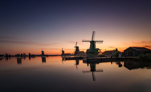 Traditional windmills by lake during sunset