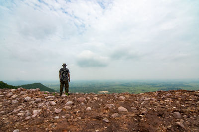 Rear view of man standing on rock against sky