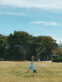 Full length of woman playing on grass against sky