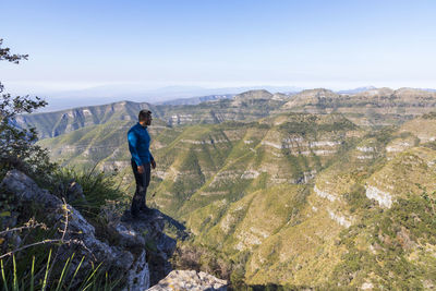 Rear view of man standing on mountain against sky