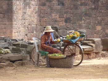 View of people sitting on stone against brick wall