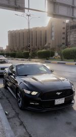 Cars on road by buildings in city against sky