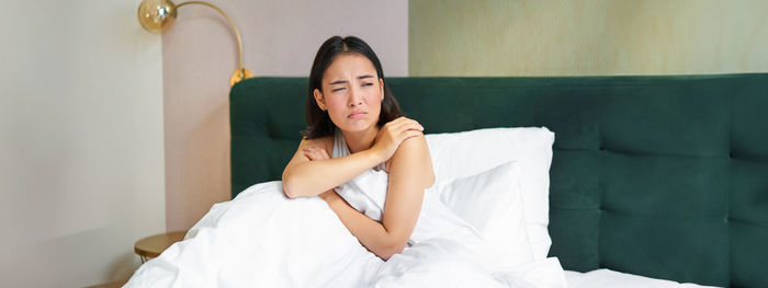 Portrait of young woman sitting on bed at home