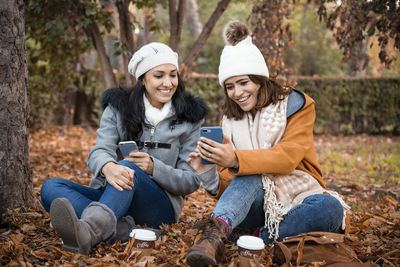 Two old girl friends looking at the smartphone screen together. close up of two old girl friends and the park background in the fall.