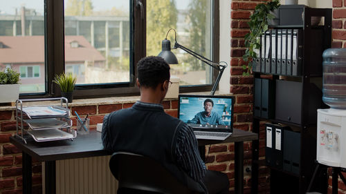 Rear view of businessman talking on video call at office