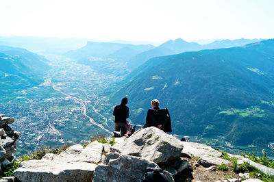 Rear view of people looking at mountains against sky