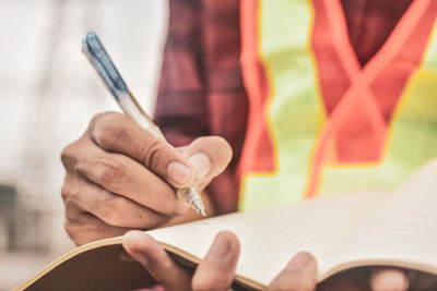 Midsection of worker writing on book