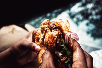 Someone's hands holding a burger that was bit into