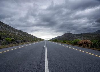 Road leading towards mountains against sky