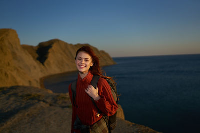 Portrait of smiling young woman standing against sky