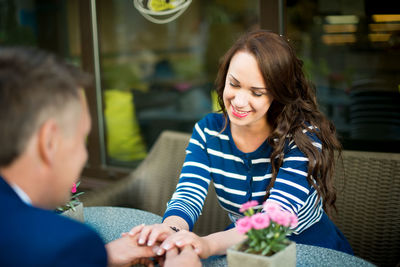 Couple holding hands while sitting in restaurant