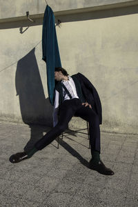 Drunk man sitting on chair against wall