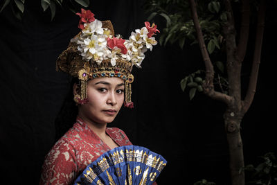 Portrait of woman in traditional clothing against tree