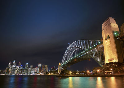 Illuminated city by river at night