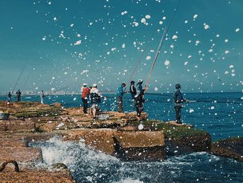 People fishing in sea against sky