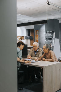 Senior couple discussing with female interior designer over at desk in store