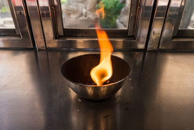 Close-up of lit candle in glass