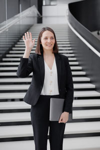 Portrait of young businesswoman standing against wall