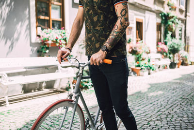 Man standing by bicycle on street in city