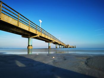 View of bridge over sea against clear blue sky